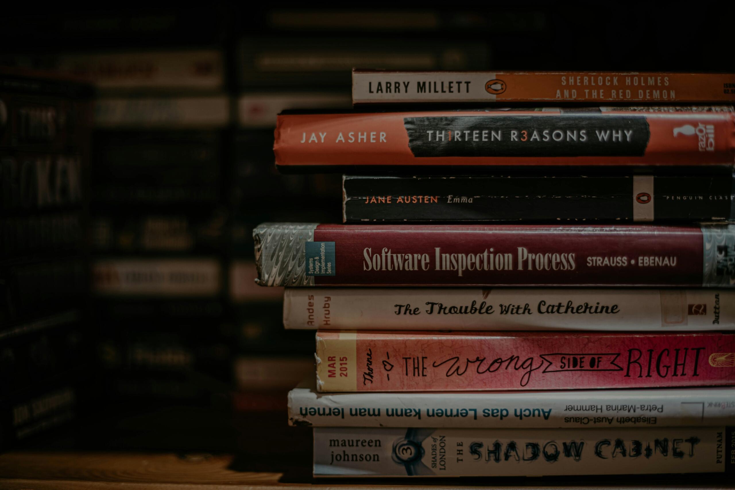Una pila de libros sobre una estantería de madera.