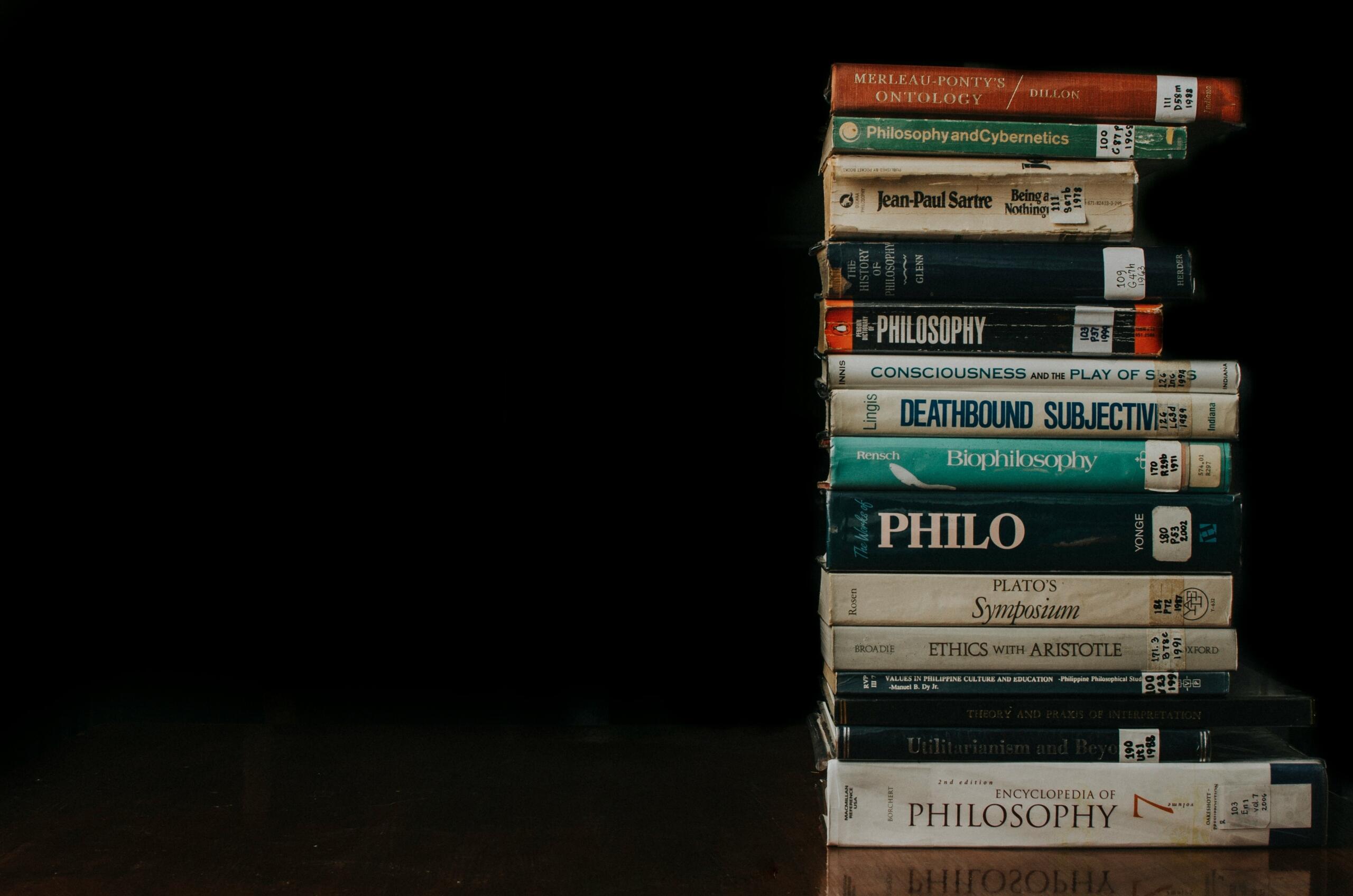 Una pila de libros apilados sobre una mesa de madera clara.