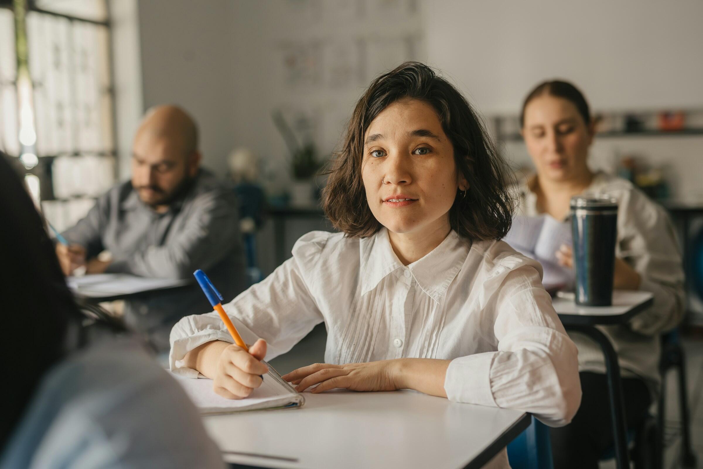 Una escena de clase con alumnos enfrascados en la escritura, pupitres con cuadernos y un ambiente de aprendizaje informal.