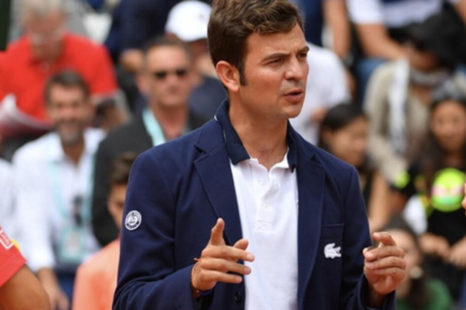 Un juez de silla de tenis conversa en la cancha, intercambiando ideas y estrategias.