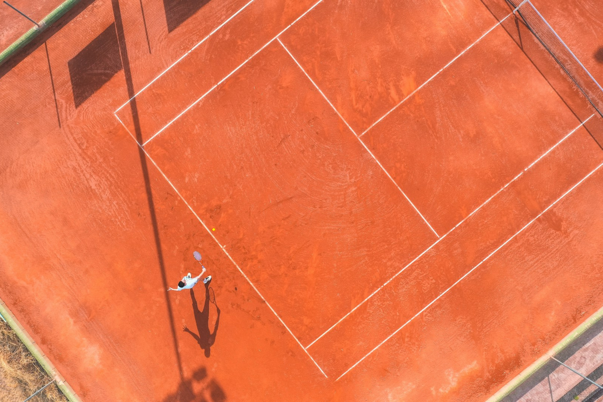 Vista aérea de una cancha de tenis, mostrando las líneas y la red en el centro del campo.