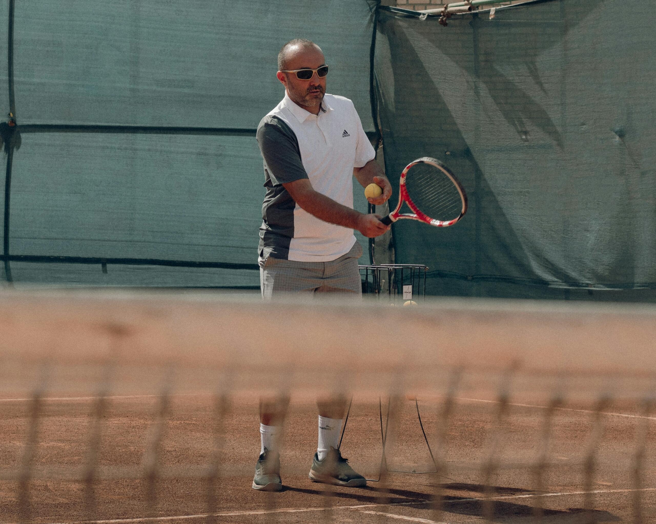 Hombre sosteniendo una raqueta de tenis en una cancha de tenis. 