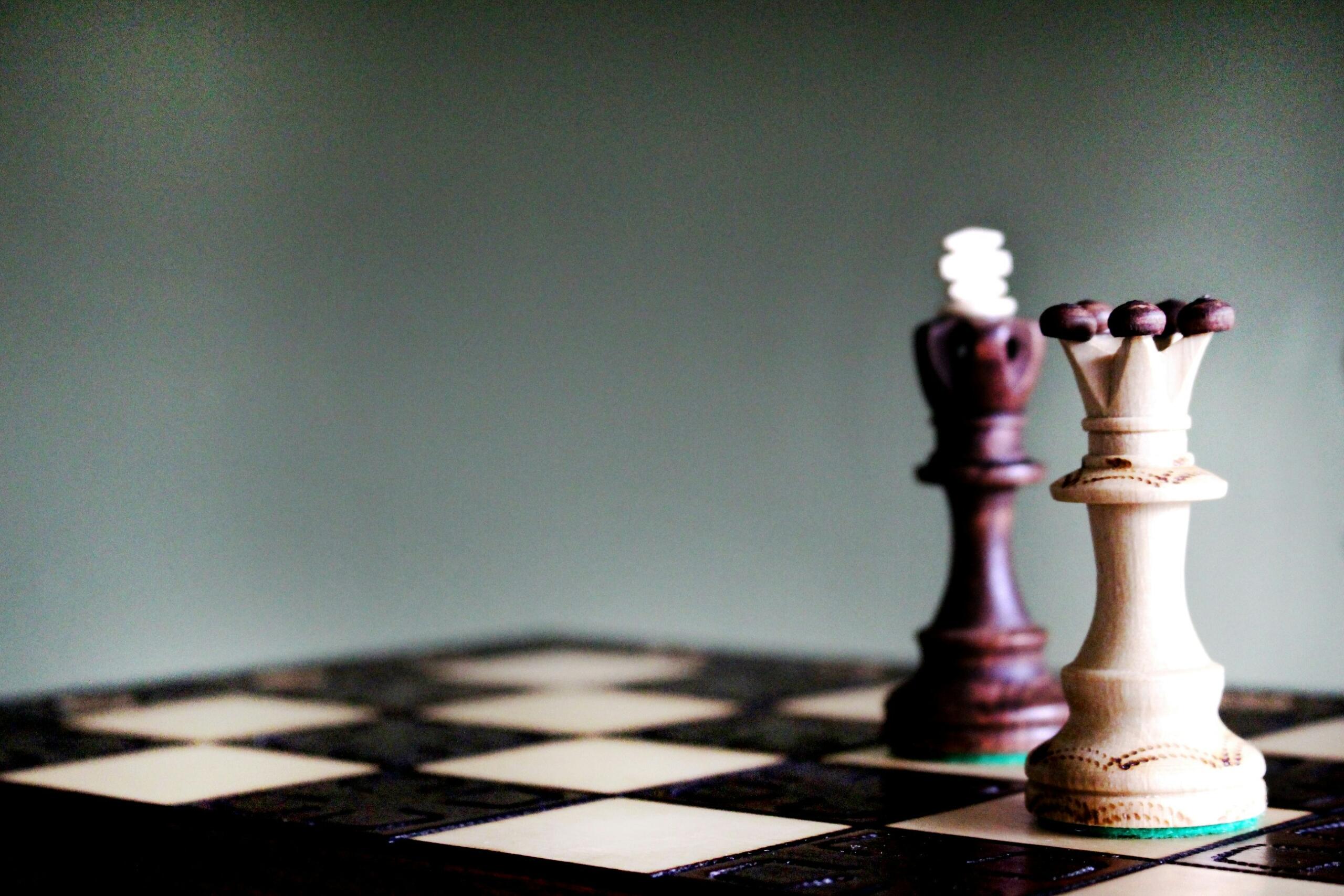 Primer plano de un tablero de ajedrez de madera con una torre blanca y otra negra sobre un fondo apagado, que simboliza la estrategia y la competición.