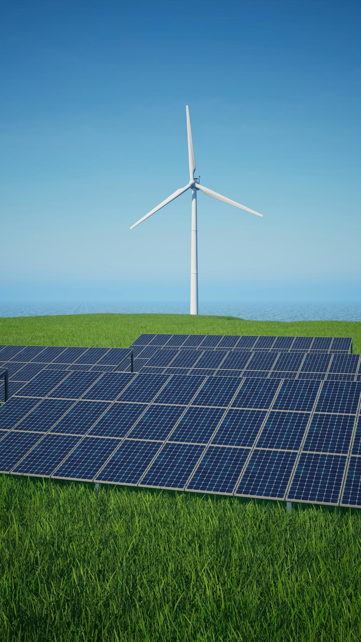 Una turbina eólica se eleva sobre un campo de paneles solares instalados sobre una exuberante pradera verde, bajo un cielo azul claro.