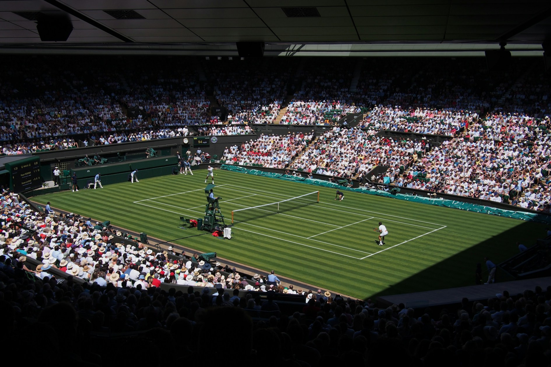 Una vibrante escena del torneo de tenis de Wimbledon con jugadores en la pista de césped, rodeados por un público entusiasta con sombreros para el sol.