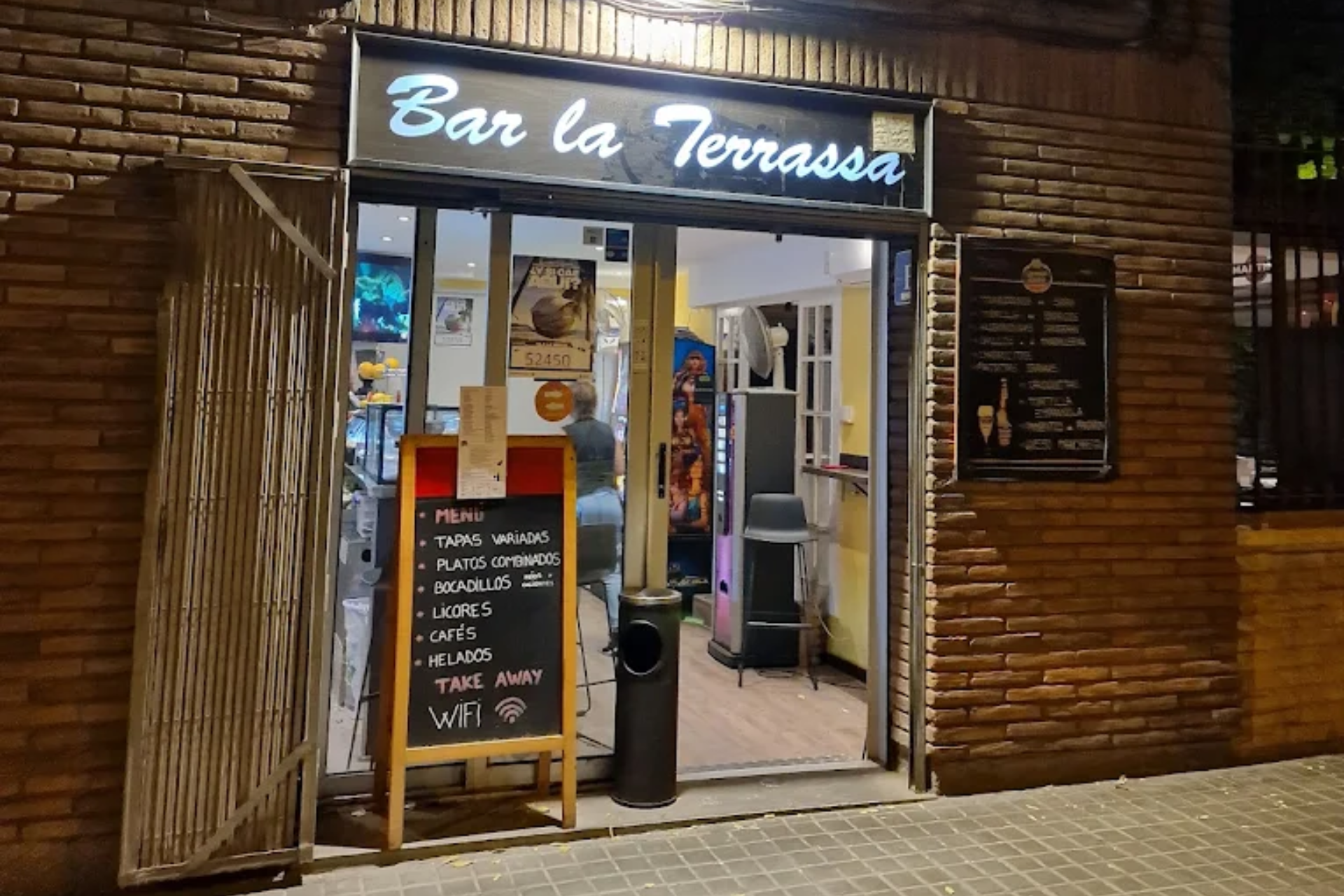 La entrada del «Bar la Terrassa», con un ambiente acogedor, el menú y un letrero de bienvenida por la noche.