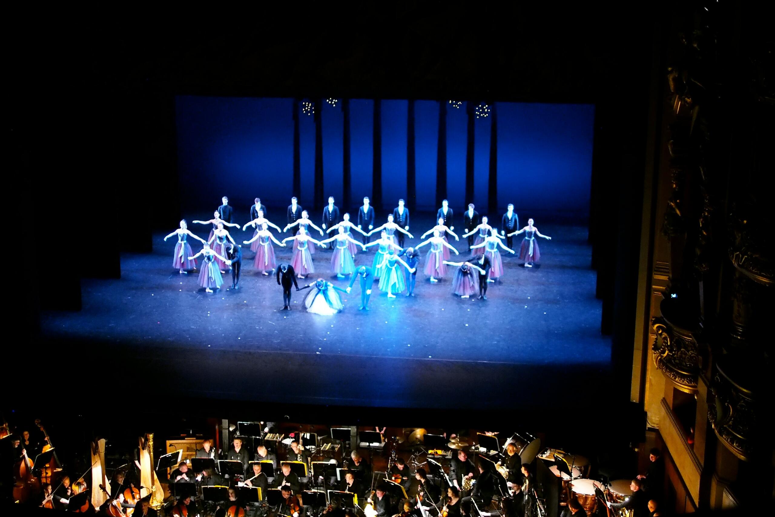 1. Un grupo de bailarines en el escenario, dirigidos por un conductor, mostrando una actuación vibrante y coordinada. 