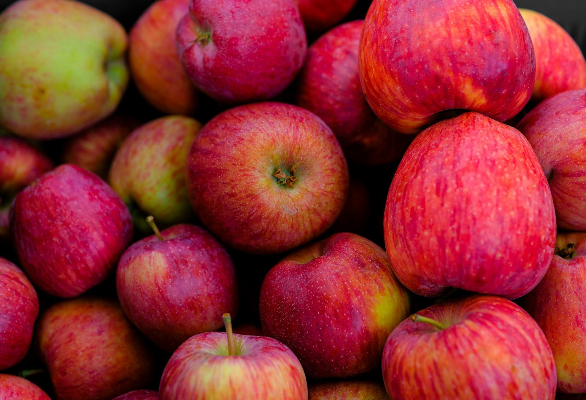 Primer plano de una pila de manzanas frescas, rojas y verdes, que muestran sus colores vivos y su aspecto saludable y crujiente.