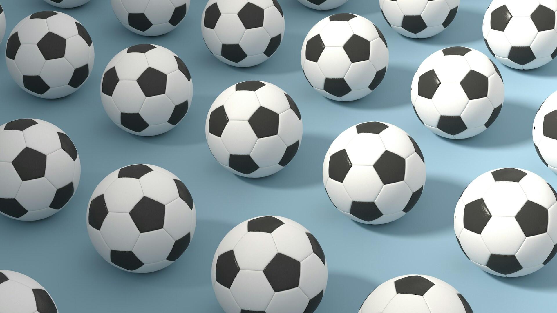 Una disposición dispersa de balones de fútbol clásicos en blanco y negro sobre un fondo azul claro, creando un divertido tema deportivo.