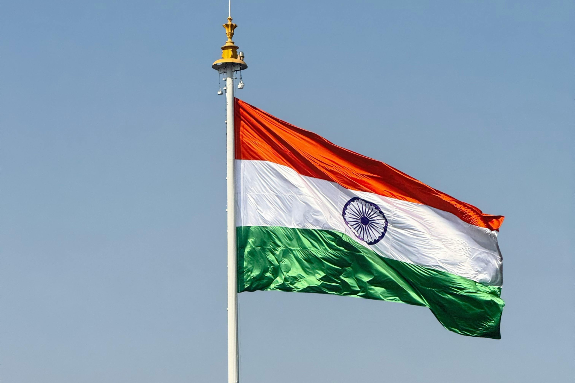 Bandera de India con tres franjas horizontales de colores azafrán, blanco y verde, y un círculo azul en el centro.