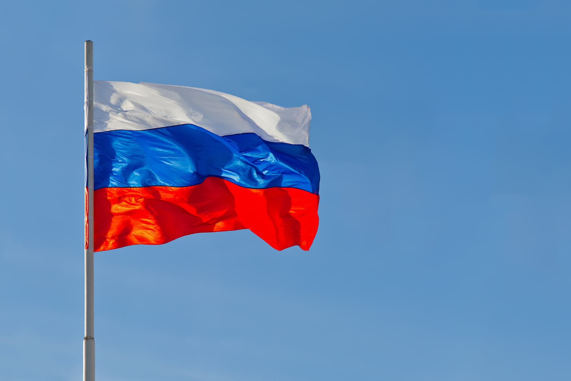 Bandera de Rusia con tres franjas horizontales de colores blanco, azul y rojo.