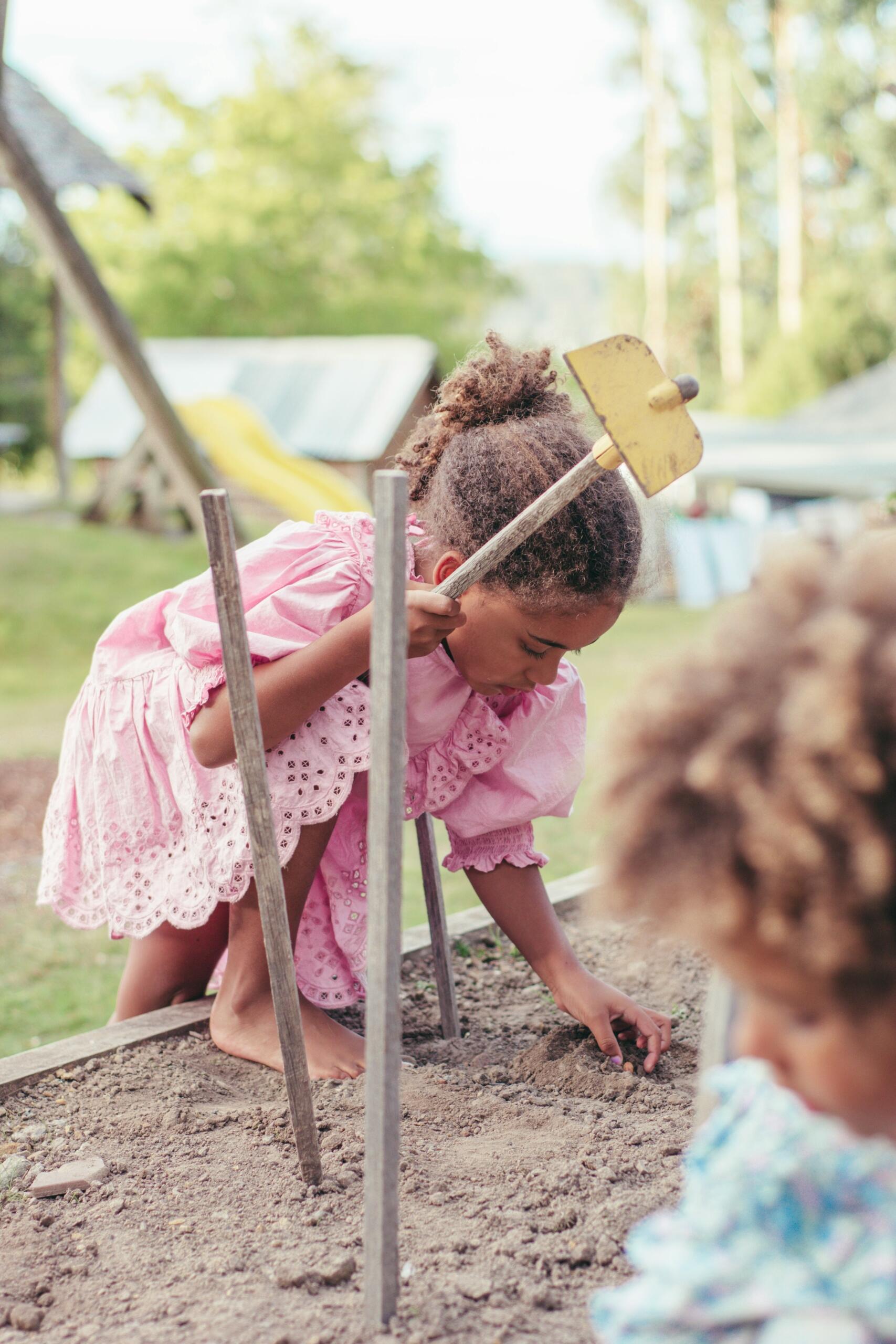 Dos niños cavando en la tierra con palas, disfrutando de una actividad al aire libre. 