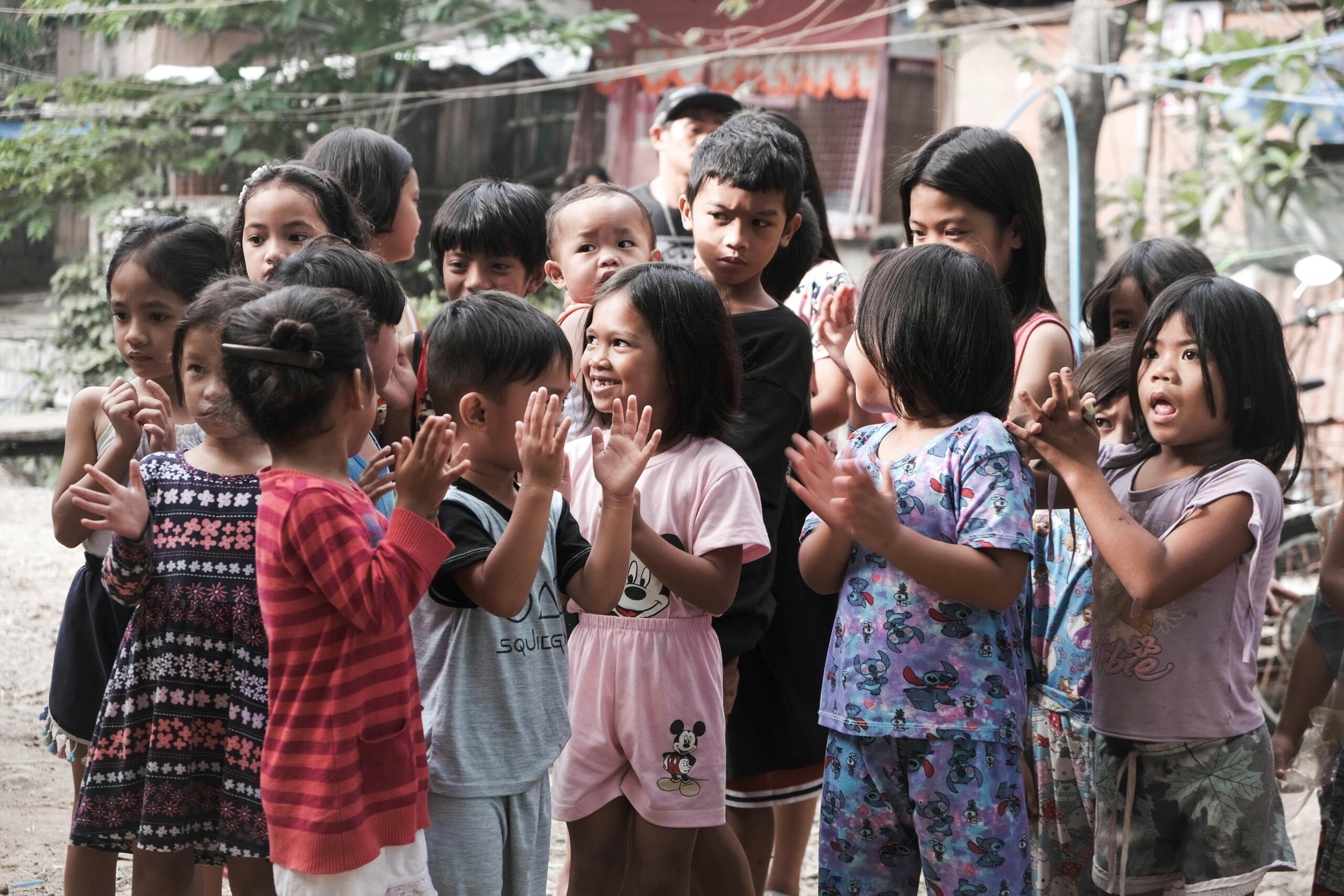 Un grupo de niños de pie frente a un edificio, sonriendo y posando para la foto. 