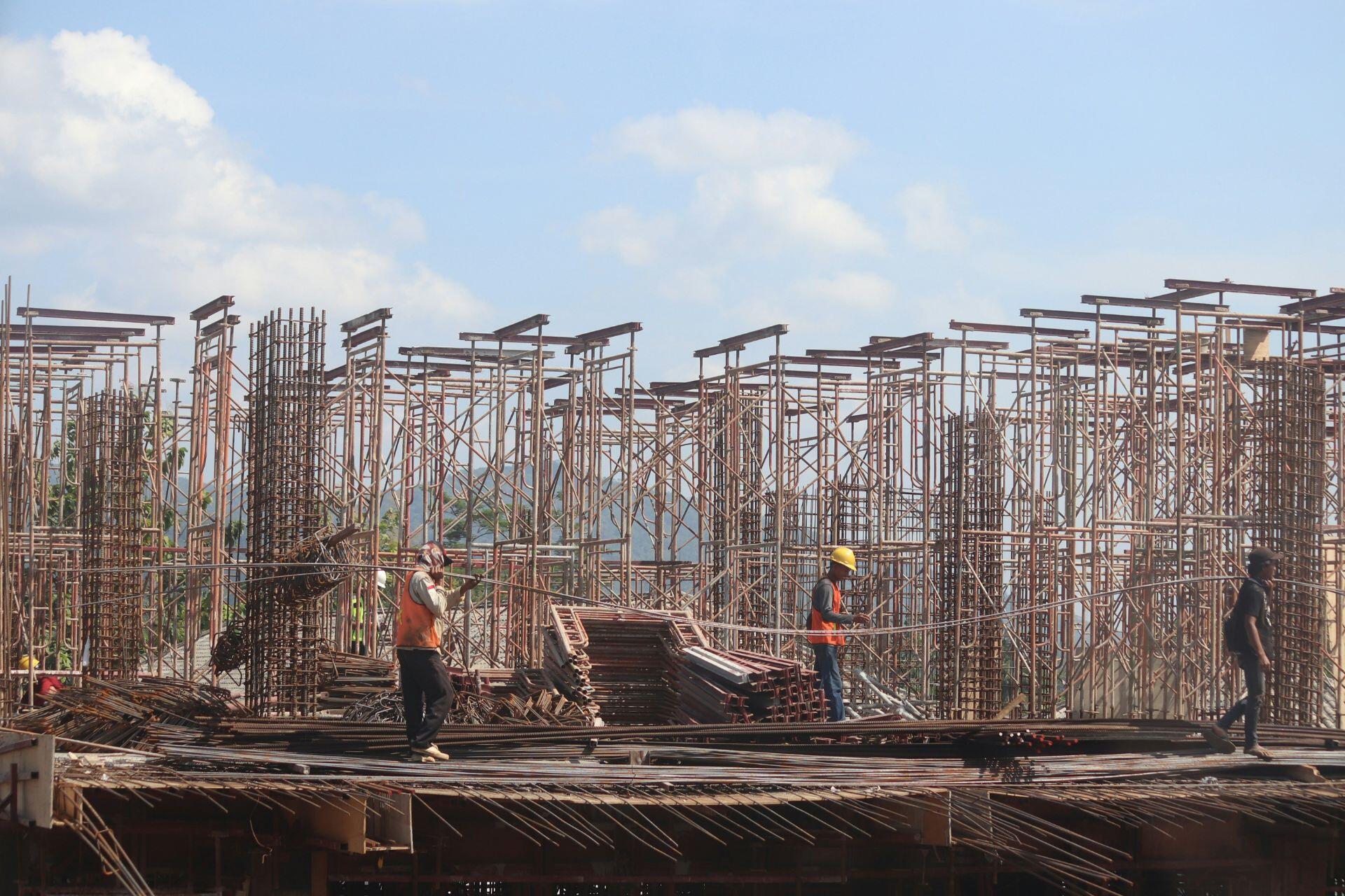 Un grupo de hombres de pie en un sitio de construcción, con herramientas y materiales a su alrededor.