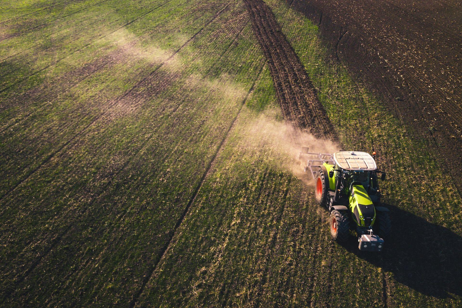 Vista aérea de un tractor aplicando fertilizante en un campo agrícola.