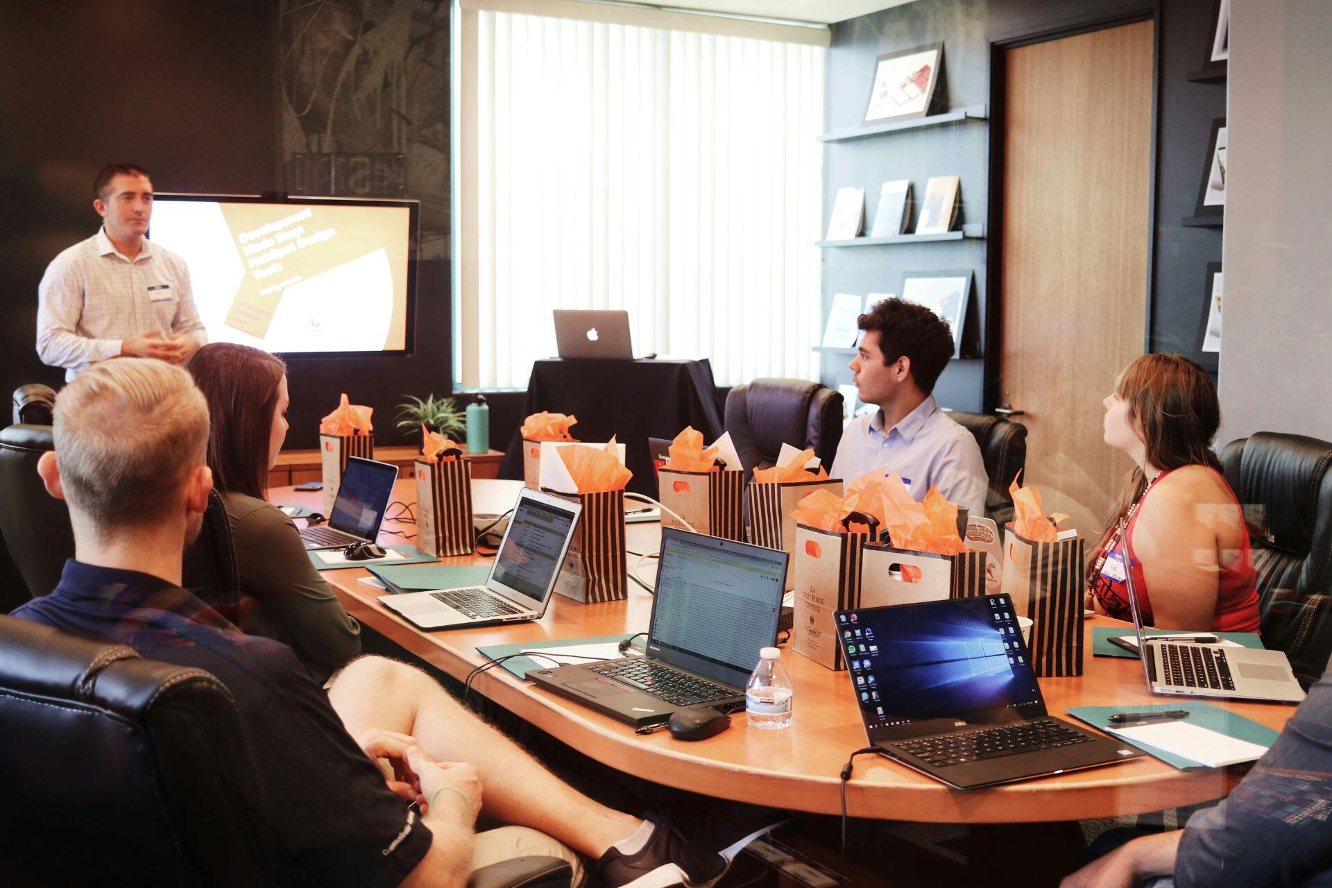 Varias personas reunidas en una mesa, utilizando laptops para trabajar en equipo y compartir ideas.