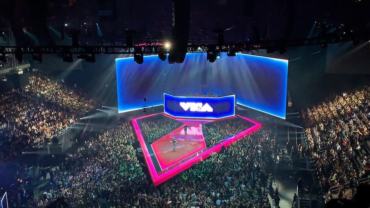 Un animado concierto en una gala de los mtv music video awards, con un gran escenario con luces brillantes y un público entusiasta.