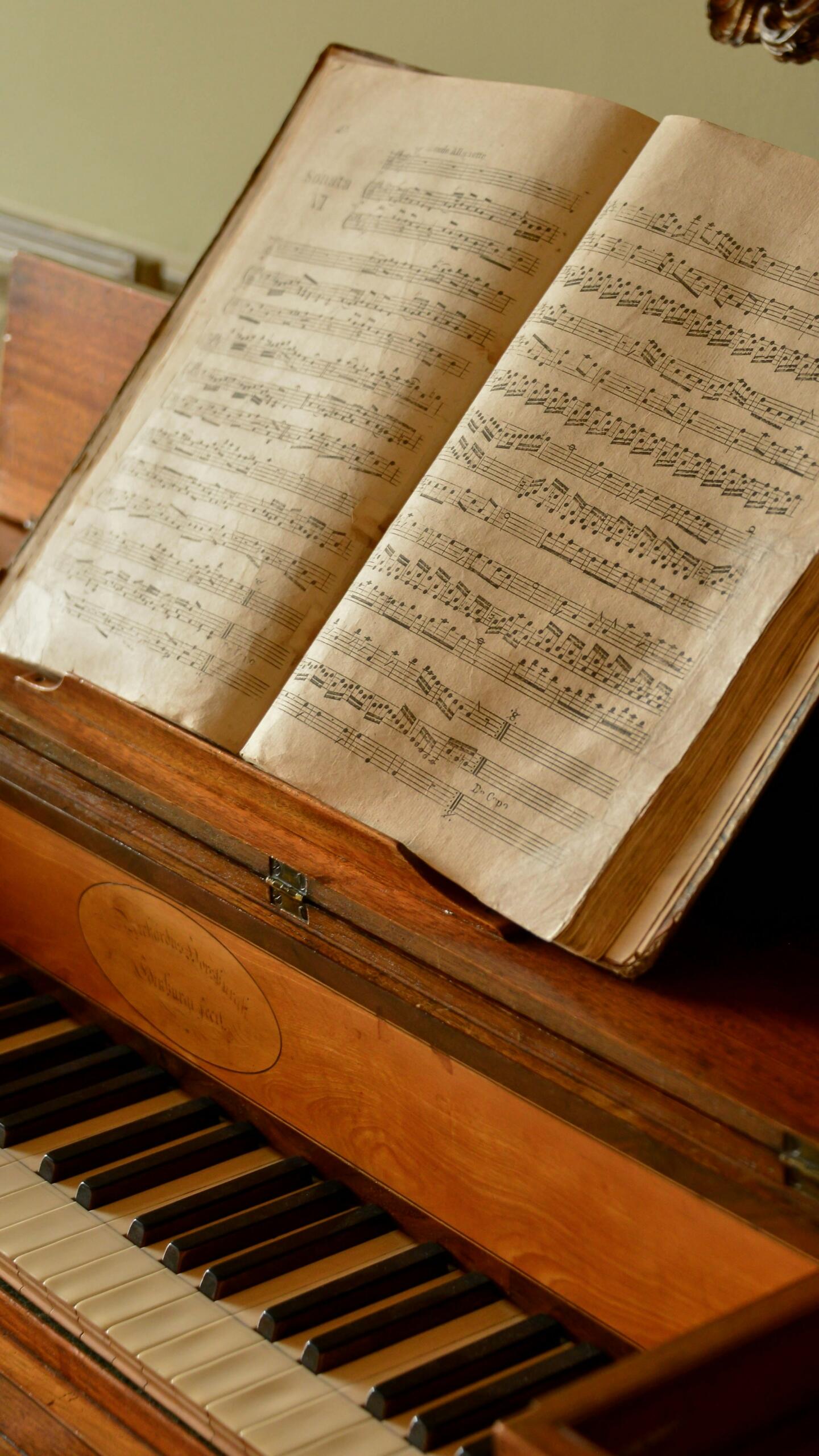 Las partituras abiertas descansan sobre el atril de un viejo piano de madera. Las teclas son parcialmente visibles, evocando una atmósfera clásica y serena.