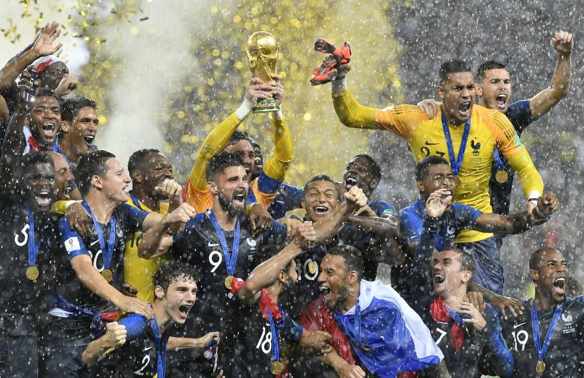 El equipo de fútbol celebra la victoria en la Copa del Mundo, alzando el trofeo en alto en medio de una lluvia de confeti dorado, bajo un arco en el que se lee «Final de la Copa del Mundo 2018».