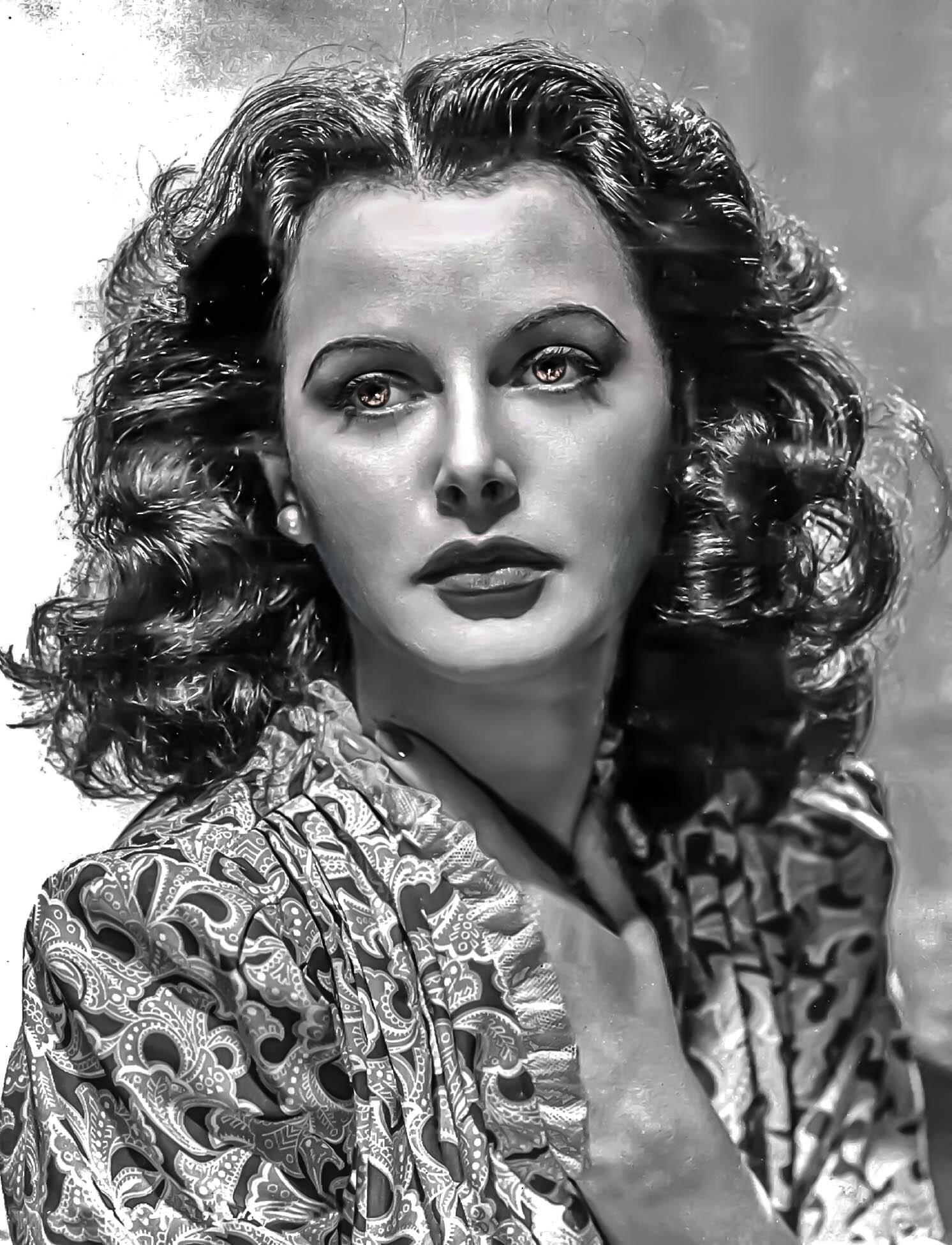 Retrato en blanco y negro de una persona con el pelo rizado que lleva una prenda estampada, con la mano tocándose el cuello en una pose clásica de estilo vintage.