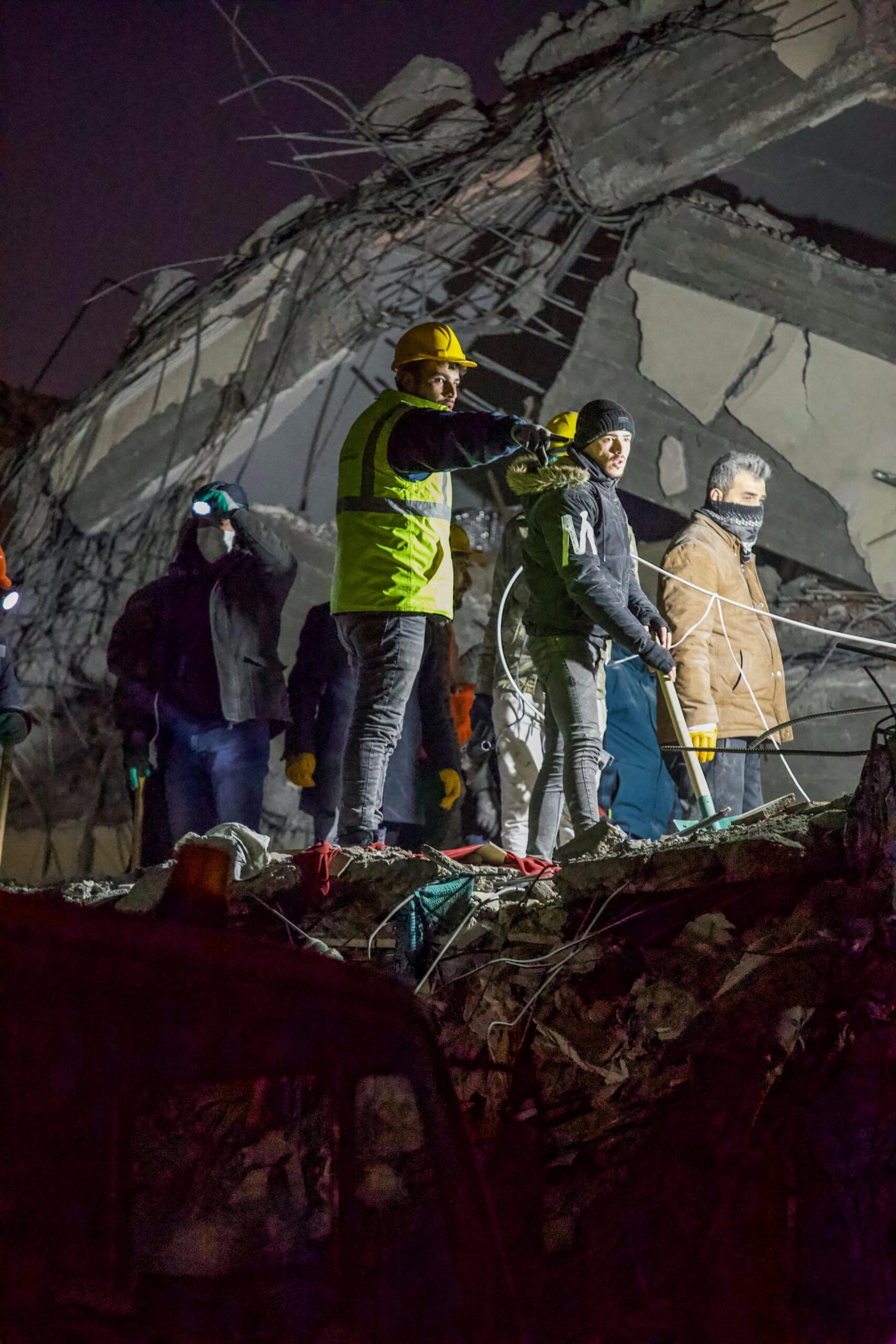 Los equipos de rescate, equipados con linternas y cascos, registran entre la noche los escombros de un edificio derrumbado, entre los restos y el metal retorcido.