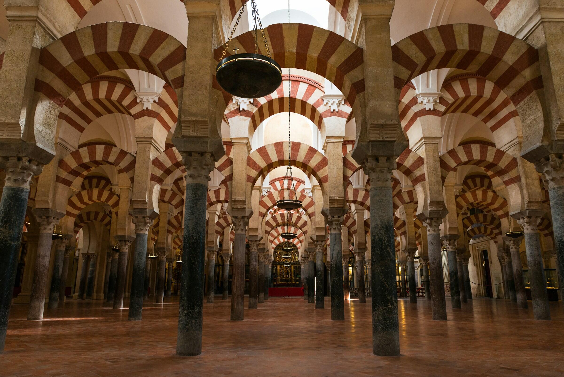 Vista interior de la Mezquita-Catedral de Córdoba, con sus emblemáticos arcos y columnas a rayas rojas y blancas.