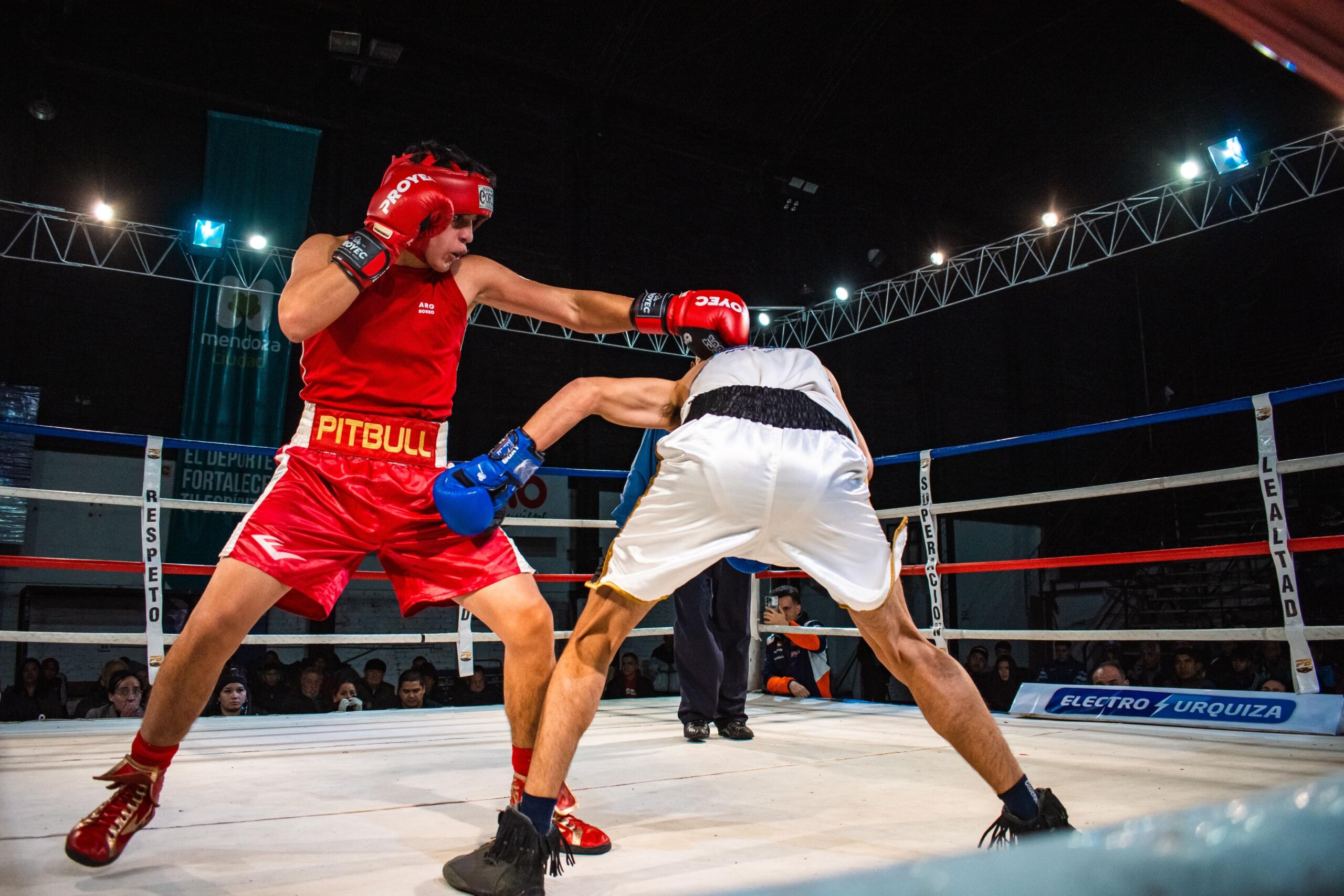 Dos boxeadores en un ring: uno lanza un puñetazo mientras el otro se defiende con los guantes en alto.