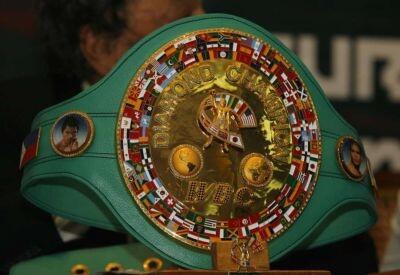 Cinturón de campeón mundial de boxeo de la WBC con el centro dorado, varias banderas nacionales y retratos en una correa de cuero verde.