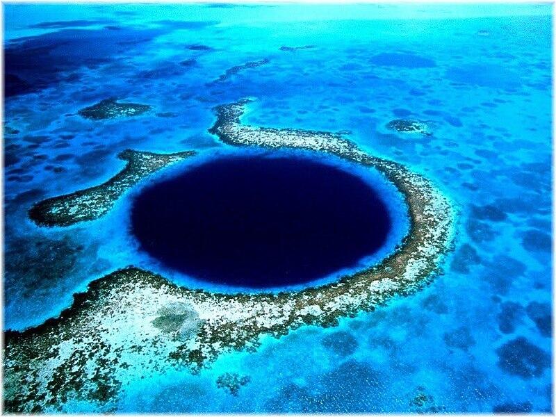 Vista aérea del Gran Agujero Azul de Belice, un profundo sumidero de color azul marino rodeado por un arrecife turquesa y por las intensas aguas del Caribe.