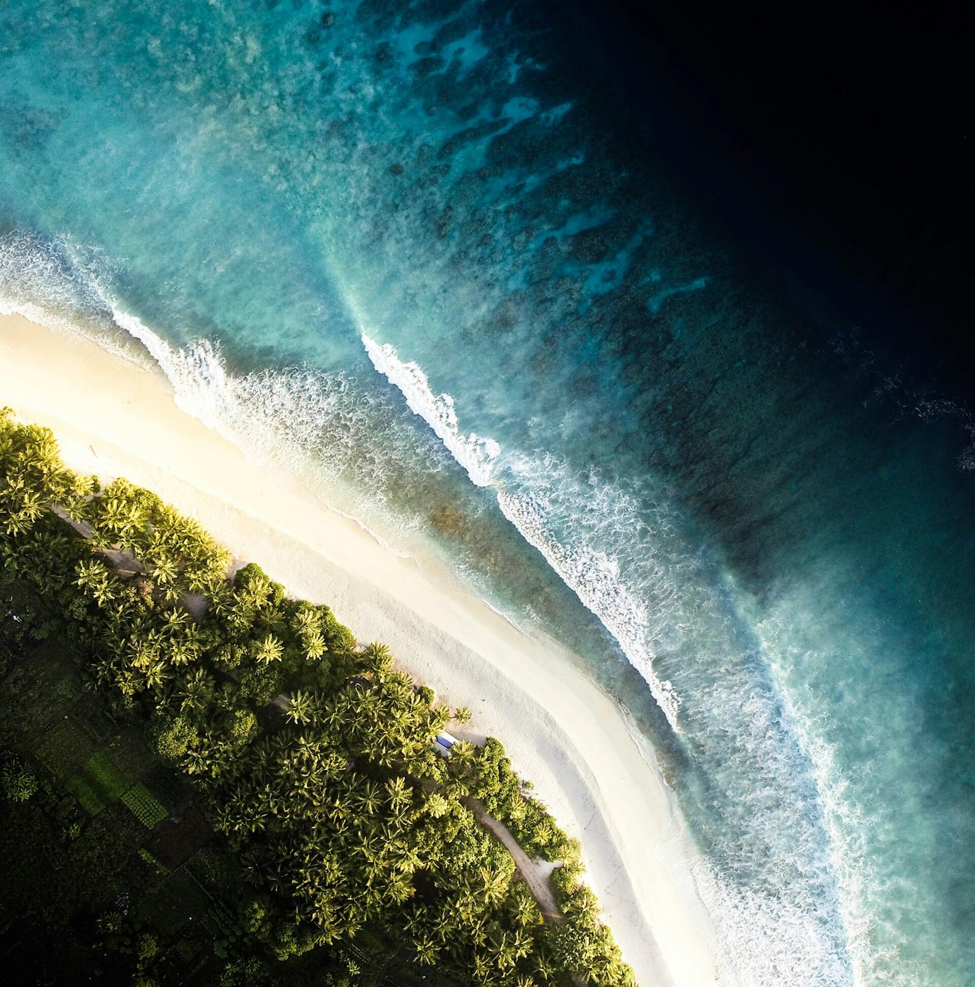 Vista desde un ángulo bajo de las olas azul oscuro del océano bajo un cielo azul brillante, creando un paisaje marino tranquilo, amplio y ligeramente dramático.