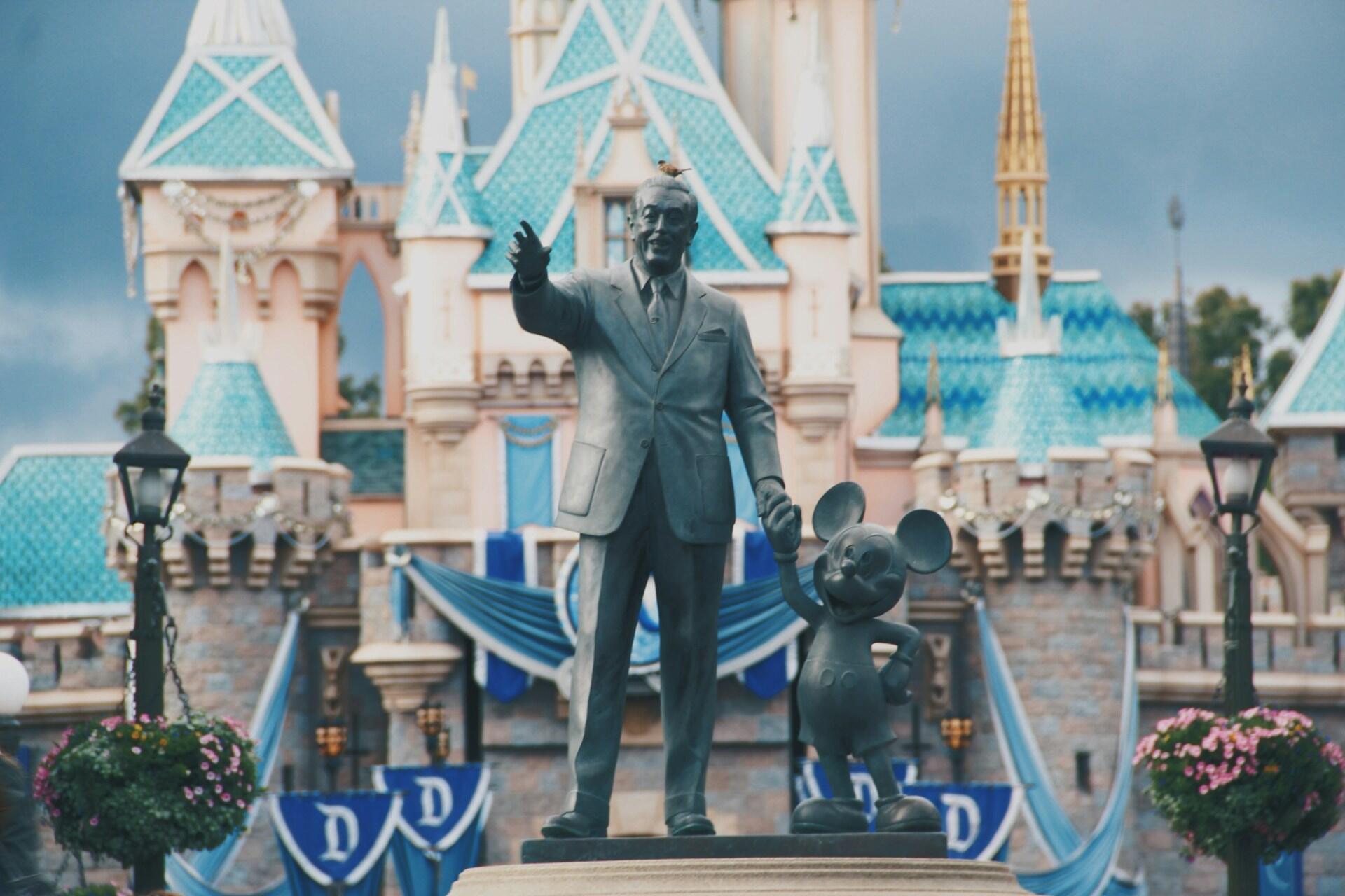 Estatua de Walt Disney y Mickey Mouse delante del Castillo de Cenicienta en un parque temático de Disney.