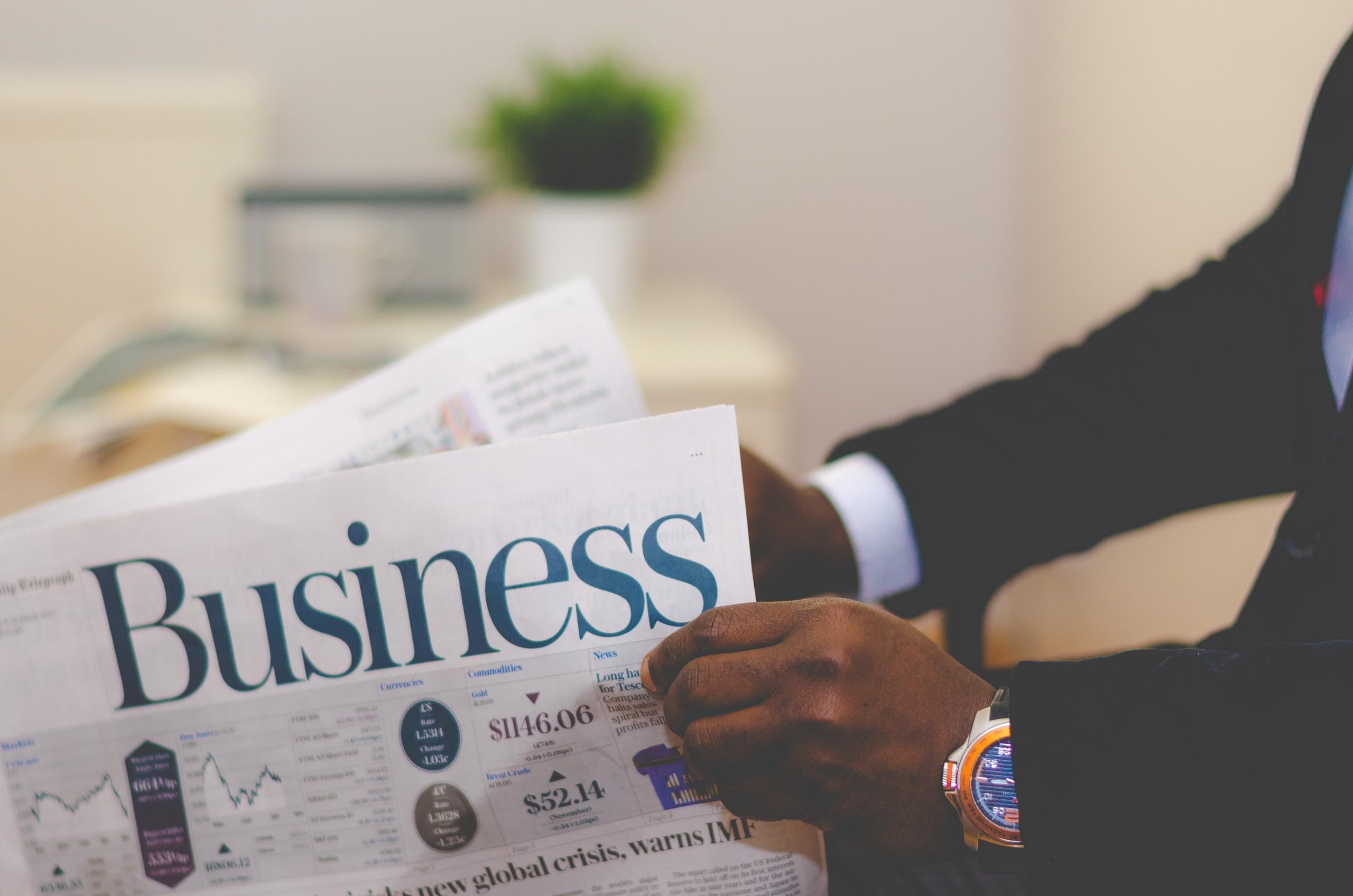 Henkilö lukemassa Business-sanomalehteä.