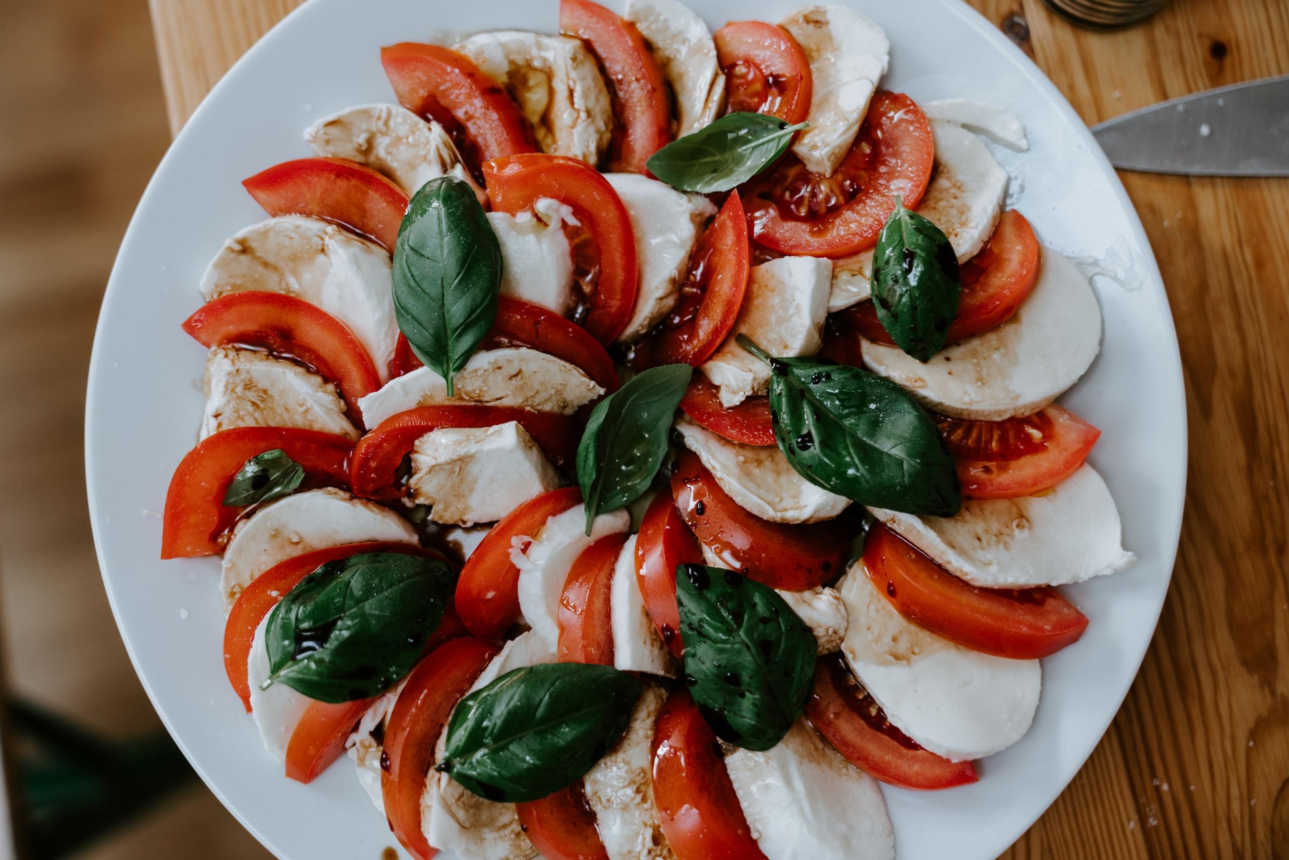 Tomaattisiivuja, mozzarellaa, basilikaa ja balsamicoa lautasella