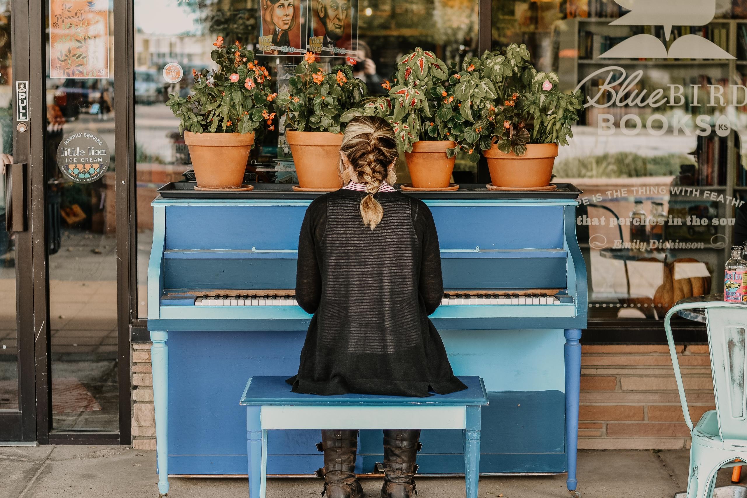 Henkilö soittamassa sinistä pianoa ulkona