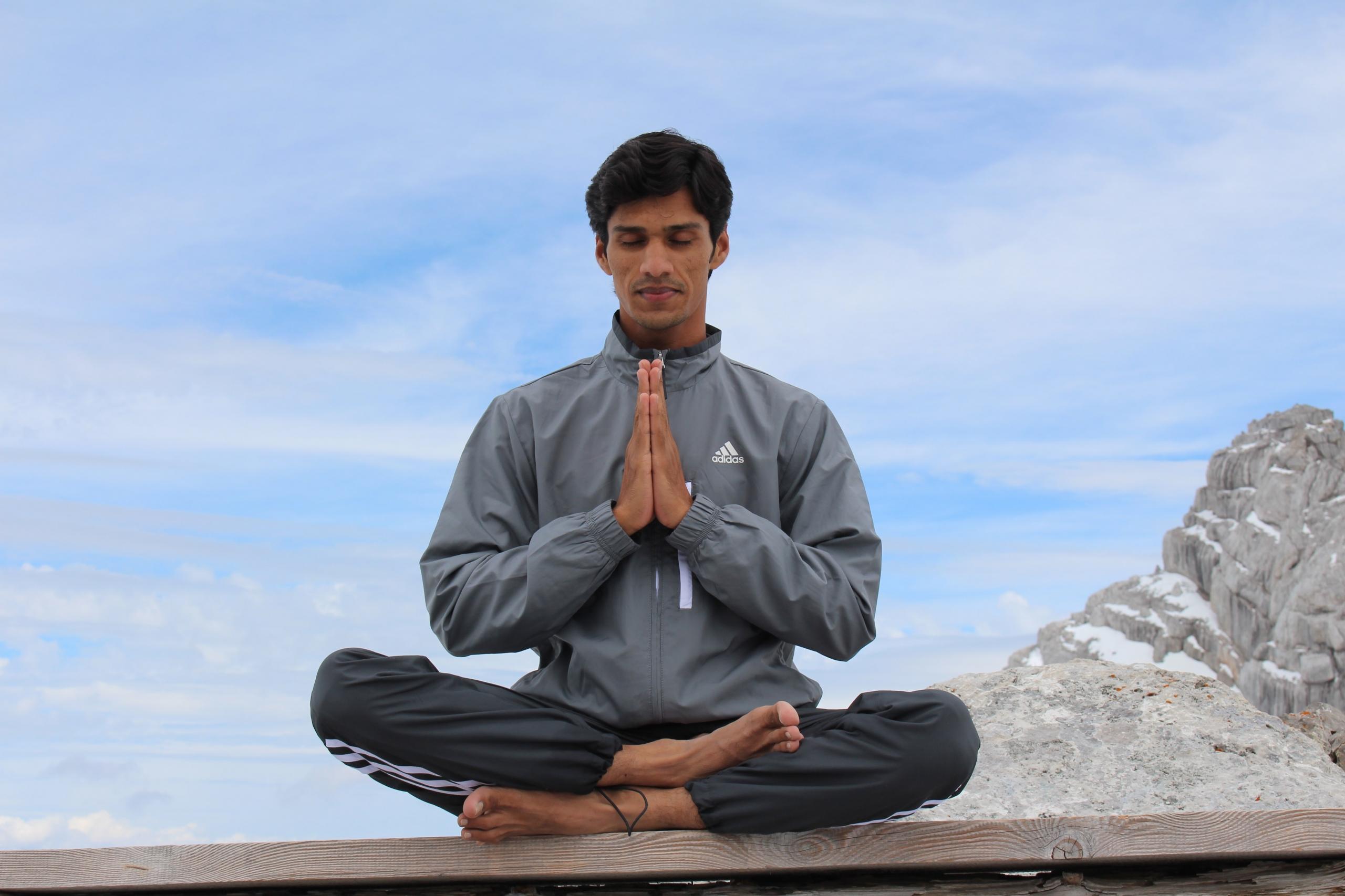 Mies tekemässä namaste-tervehdystä lootusasennossa