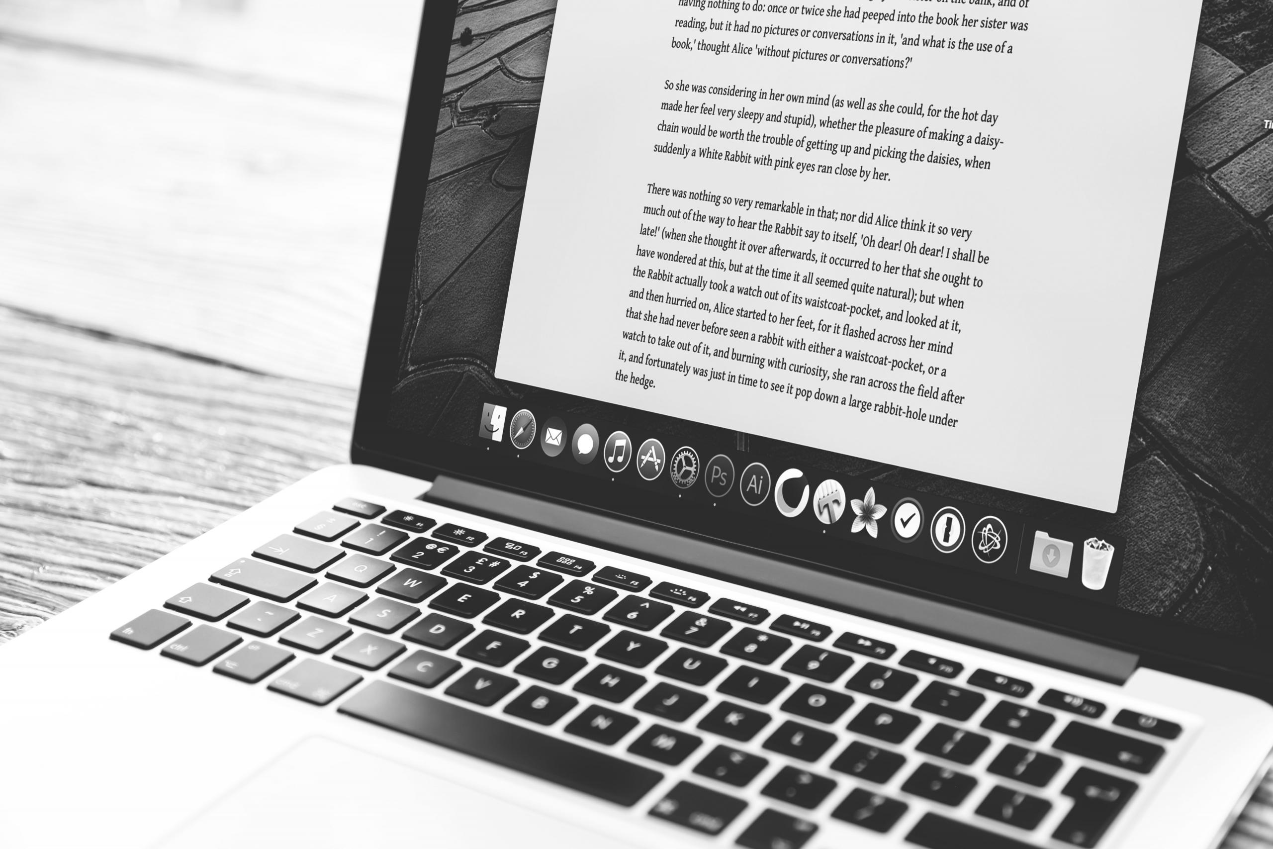 Valkoinen MacBook, jonka näytöllä tekstiä