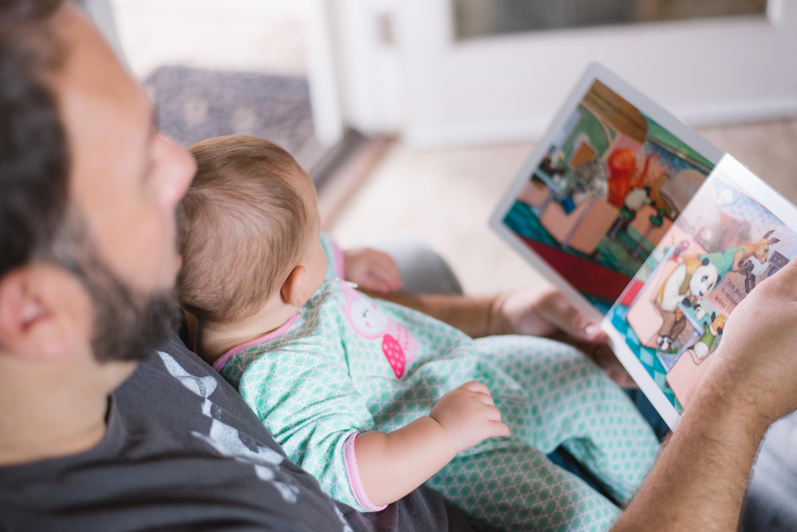 Mies lukemassa kuvakirjaa pienelle lapselle
