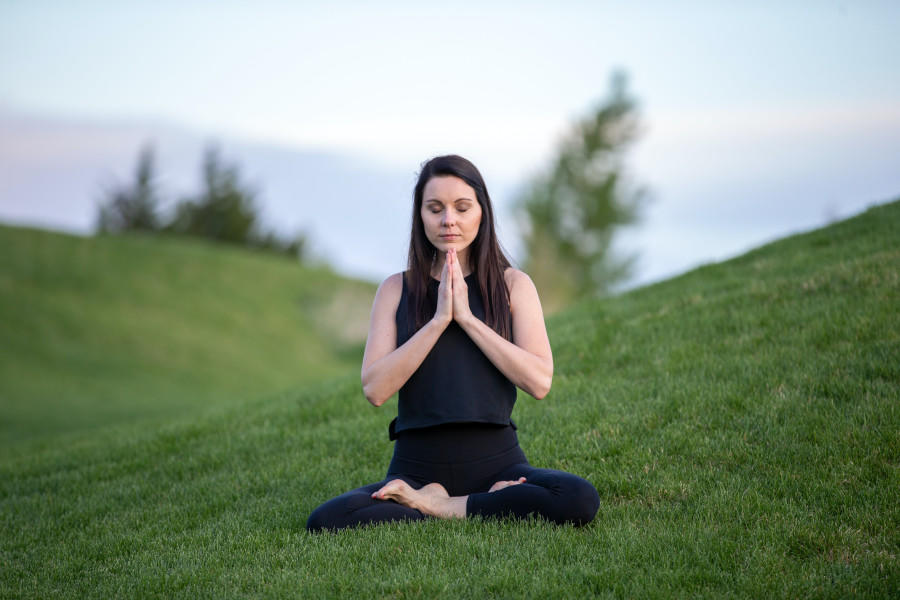 Nainen meditoimassa ulkona nurmikolla