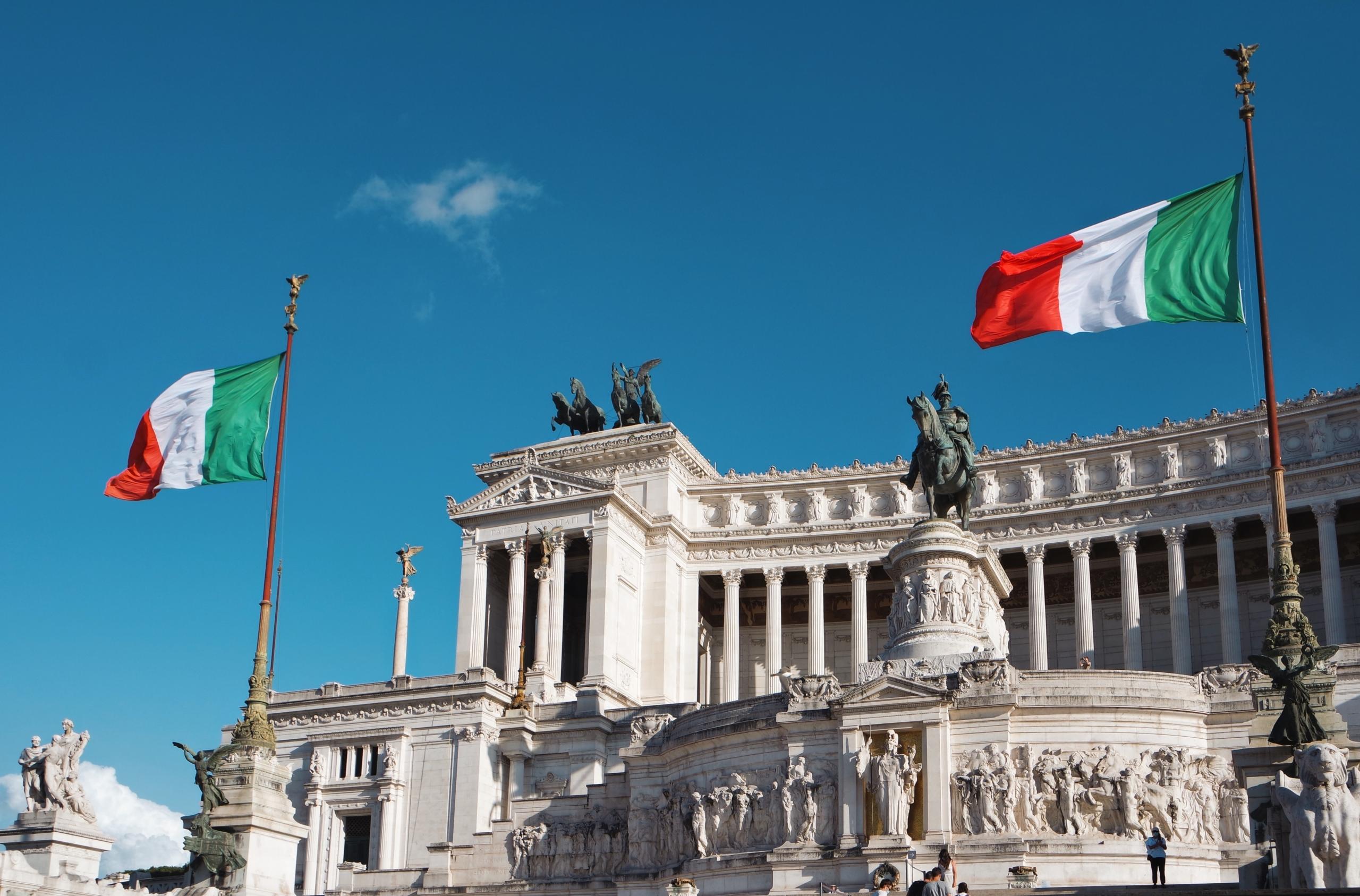 Italian lippuja valkoisen rakennuksen edessä