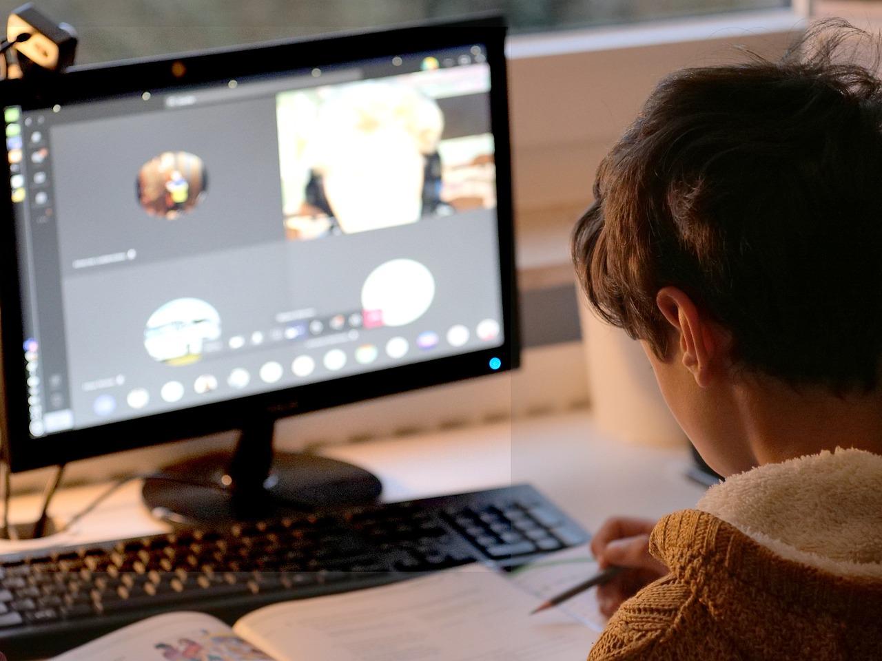 Henkilö tutkimassa oppikirjaa videopuhelun aikana