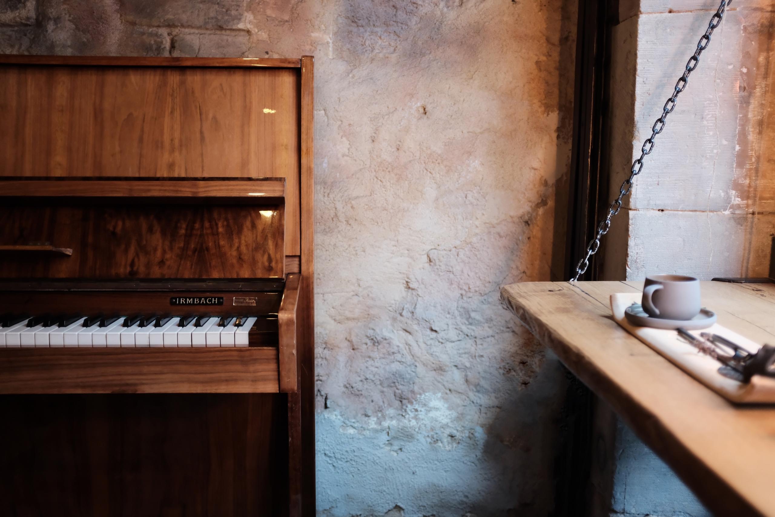 Ruskea akustinen piano kiviseinää vasten