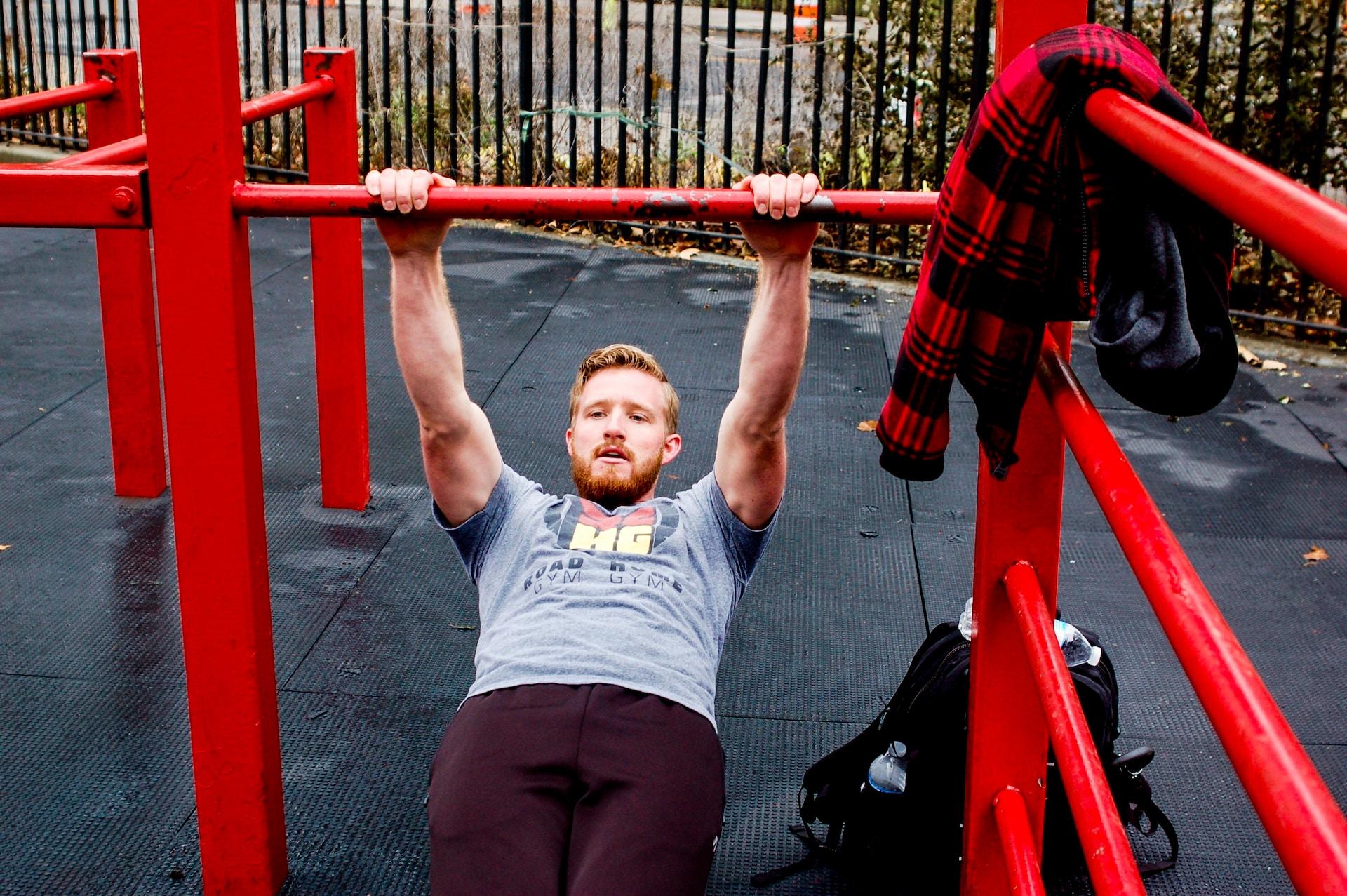 Henkilö roikkumassa kaksin käsin tangosta ulkokuntoilupaikalla