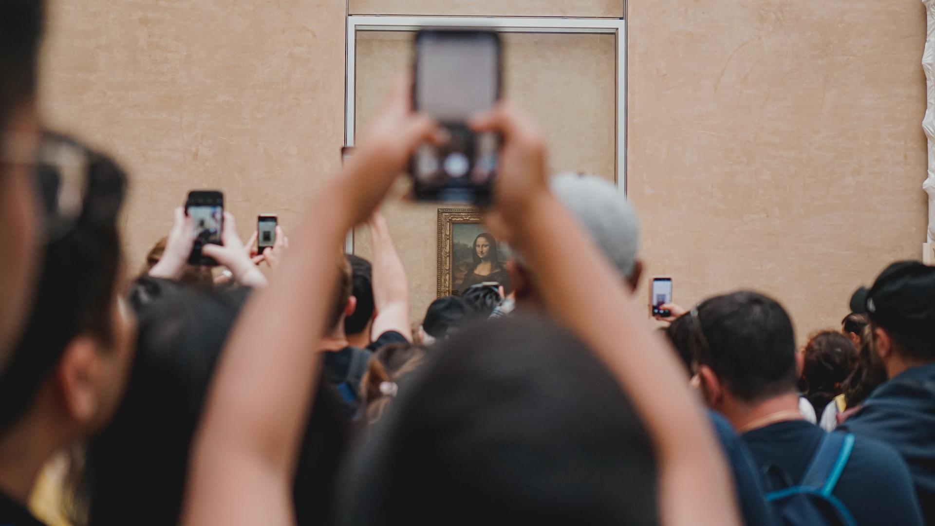 Joukko ihmisiä ottamassa valokuvia Mona Lisa -maalauksesta