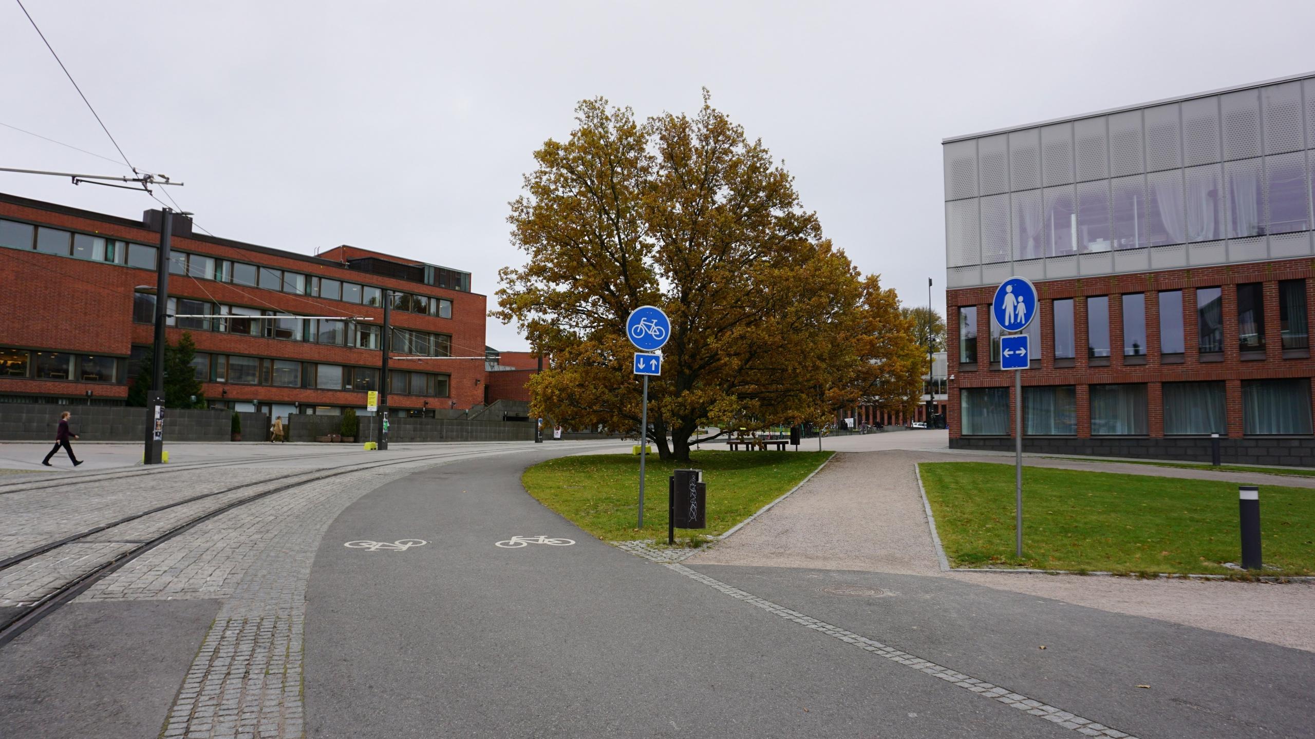 Raitiovaunulinja, pyörätie ja käveltie rakennusten välissä