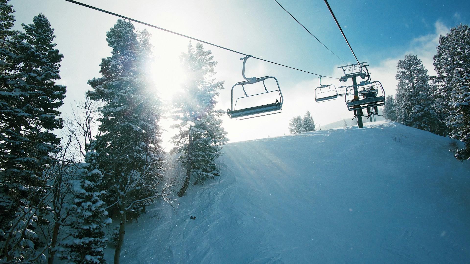 Tuolihissi, jonka kyydissä matkustajia auringon paistaessa taustalla