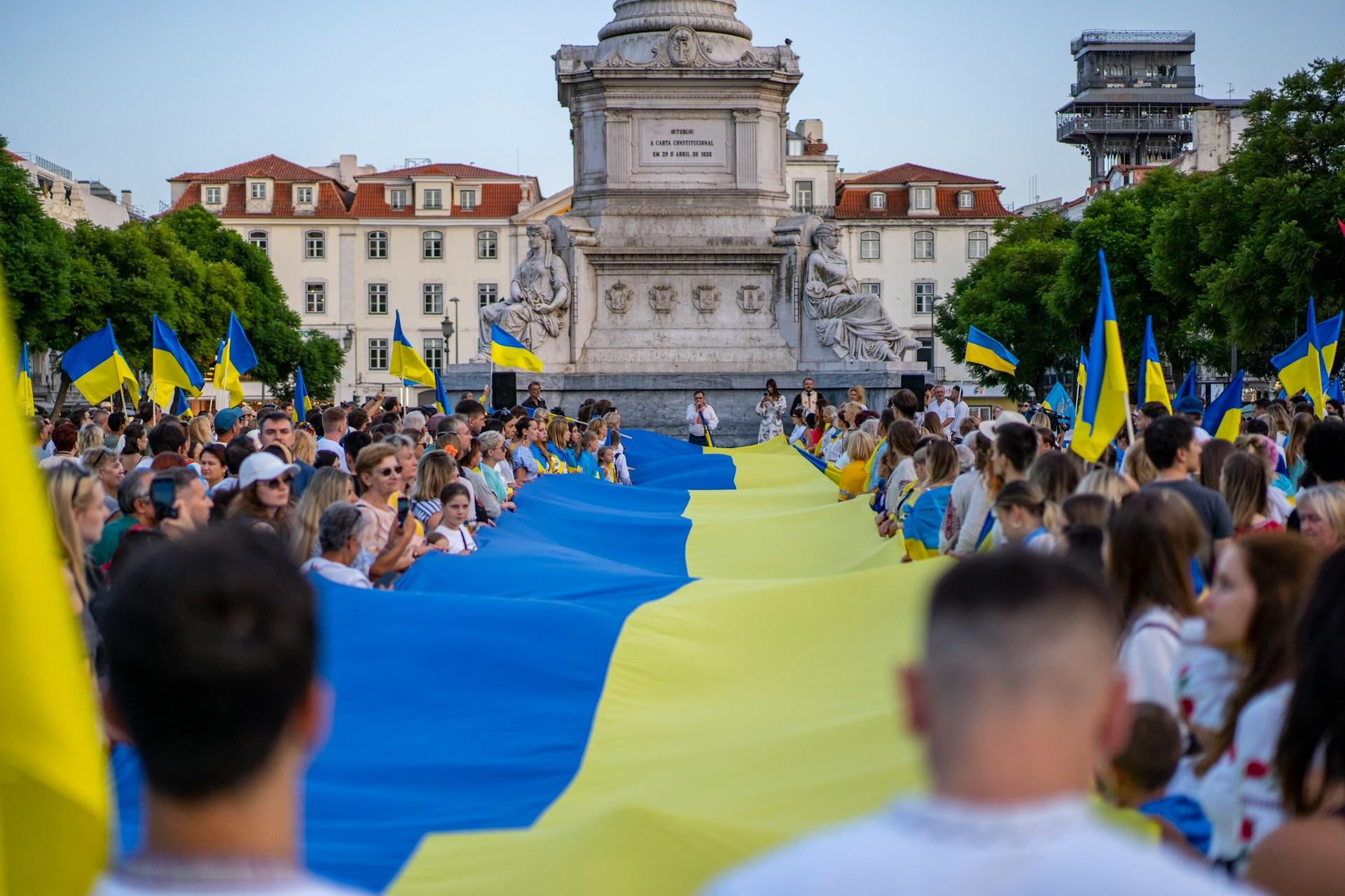 Joukko ihmisiä kannattelemassa suurta Ukrainan lippua