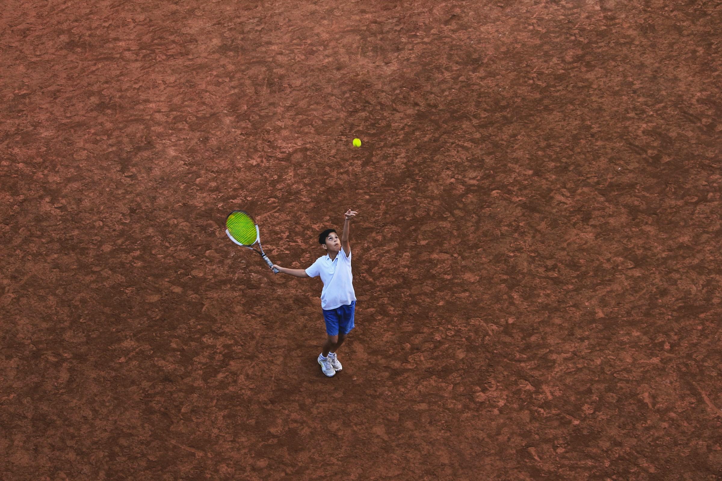 Lapsi pelaamassa tennistä