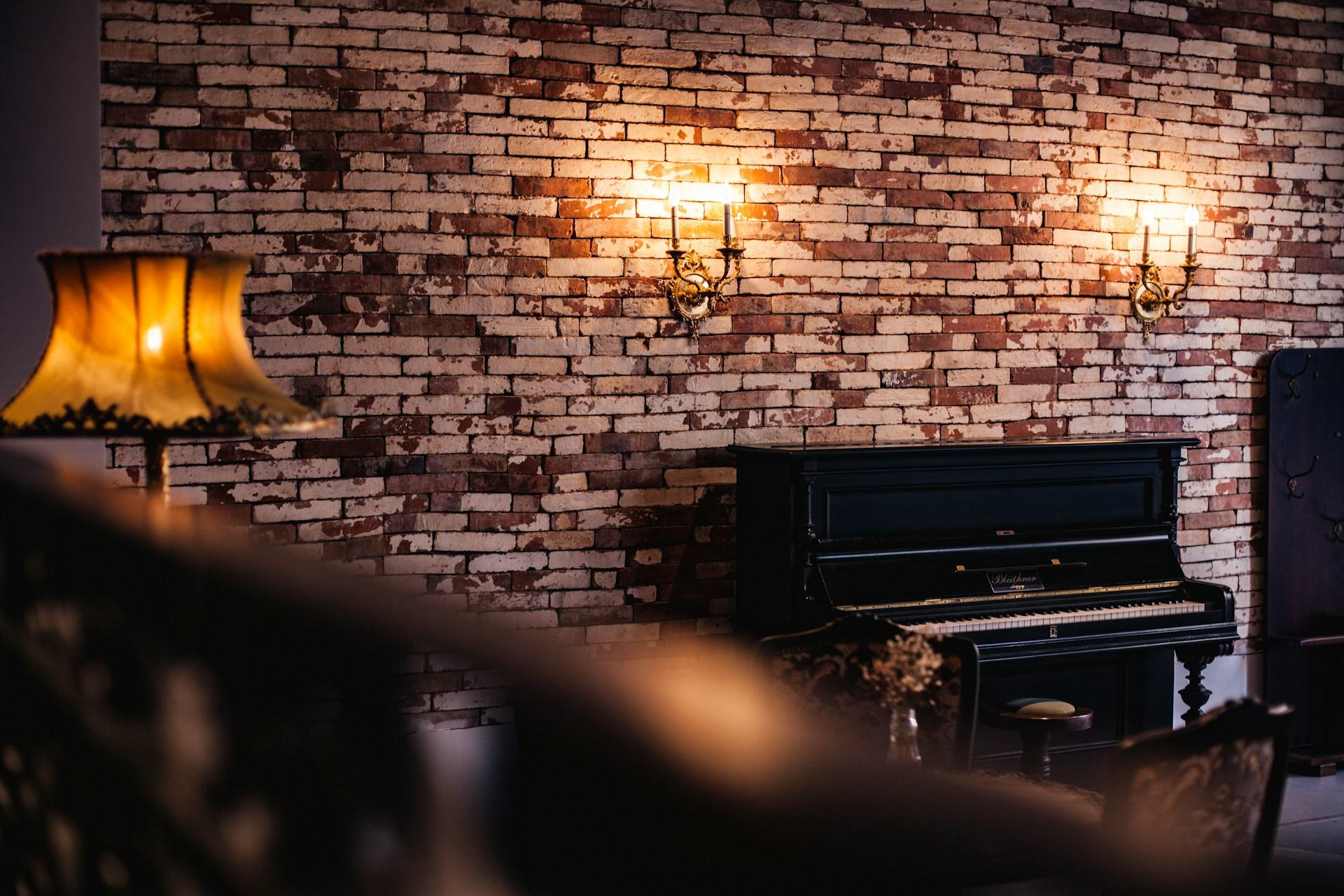 Musta piano tiiliseinää vasten
