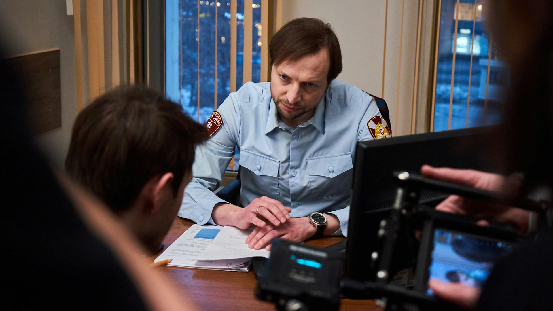 Mies istumassa pöydän ääressä vaaleansinisessä kauluspaidassa