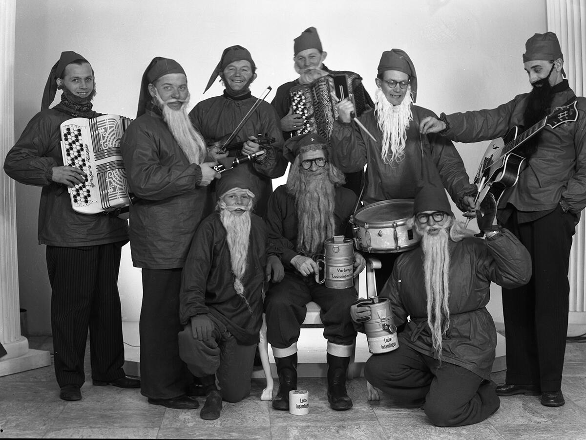 Mustavalkokuva orkesterista tonttupuvuissa